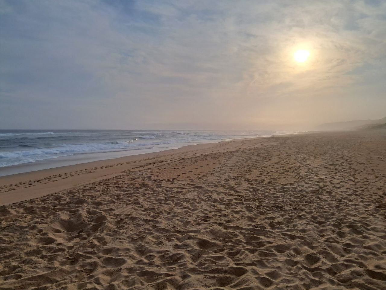 Sunset haze over Wilderness Beach with footprints and tyre tracks in the sand