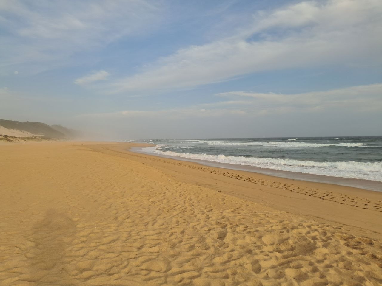 Footprints along the wet shoreline at Wilderness Beach in the evening light